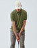 A light beige unstructured cotton twill cap worn by a person in a green polo and grey pants, indoors.