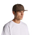 A brown cap worn by a man with a neutral expression, featuring a simple design and a logo.