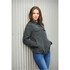 A woman leans against a wall wearing a dark green quilted jacket with buttons and chest pockets.