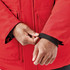 A red Men's Denali Parka featuring a black cuff and hands adjusting the sleeve. The parka has pockets.