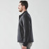 A men's black jacket with a button-up front and long sleeves, displayed on a model from the side.