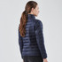 A women's jacket in navy blue with a quilted design and a collar, featuring a logo at the back.