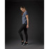 A woman in a navy crew neck t-shirt and black leggings stands in profile against a dark background.