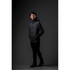 A model wearing a black Men's Patrol Softshell jacket, standing against a dark background. The jacket features a hood and has branding.