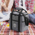 A drink bottle cooler bag made of grey recycled felt, featuring black straps and a logo, on a picnic blanket.