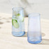Two highball glasses in light blue, one filled with water and cucumber slices, displayed on a marble surface.