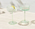 A set of two glass coupe cocktail glasses in a soft green hue, presented in a gift box.