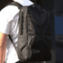 A black laptop backpack with multiple compartments and a logo, worn on a person's back.