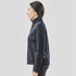 A women's navy knit jacket featuring a high collar and zippered pockets, displayed from the side.