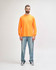 An orange long sleeve t-shirt worn by a standing male model, paired with black pants and sneakers.