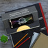 A grey Atoll Notebook with a phone and graphic design on top, alongside a small plant and various stationery items.