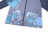 A grey school wear jacket featuring blue patterned designs and a zip closure. It includes a logo.