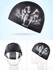 A black swimming cap featuring a graphic design of a fierce face with red eyes. It has a logo on it.