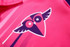 A pink sports uniform featuring a stylised owl logo with wings, designed for squash.