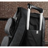 A black and grey compu-backpack featuring a retractable handle and a side pocket, set against a brick background.