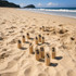 A set of wooden skittle pins numbered 1 to 12 arranged in sand on a beach, with a scenic ocean backdrop.