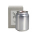 A silver can candle sits beside a square grey box, showcasing a sleek design and minimal branding.