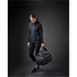 A black duffel bag with blue accents, held by a person wearing a black jacket and leggings.