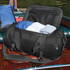 A black duffle bag with clothes inside, featuring a zippered top and a logo on the side.