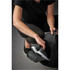 A person reaching into a black duffle bag, revealing a compartment for shoes or sneakers.