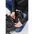 A black backpack with a person inspecting the interior, revealing a compartment for a laptop or device.