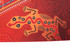 An orange and red beach towel featuring a stylised lizard design with dots and intricate patterns.