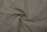 A fabric swatch of light beige windbreaker pants, featuring a smooth texture and a subtle spiral fold.