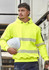A bright yellow unisex hoodie with segmented tape and a hood, held with a white hard hat against a construction backdrop.