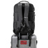 A black backpack with padded straps sits atop a silver suitcase, featuring a branding logo on the front.
