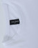 A white long sleeve tee shirt with a rounded neckline and a tag displaying branding.