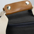 A wine cooler bag featuring a sleek black exterior and a brown leather handle, with metal rivets for added durability.
