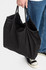 A black nylon tote bag with two compartments, being held by a person in casual attire.