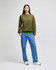 An olive green sweater worn by a model with blue jeans and white shoes, standing against a light background.