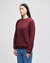A maroon crewneck sweatshirt with long sleeves, featuring a logo, displayed on a model.
