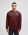 A maroon adult crewneck sweatshirt is worn by a model, featuring a subtle logo on the sleeve.