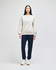 A woman stands in a light grey Champion Powerblend® adult crewneck sweatshirt and navy jogger pants, wearing white sneakers.