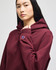 A maroon hooded sweatshirt featuring a logo on the sleeve, modelled by a person with long hair.