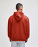 A red pullover hooded sweatshirt with a large hood, seen from the back. Features a logo on the garment.