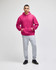 A pink pullover hooded sweatshirt with a front pocket, paired with grey sweatpants and black shoes.
