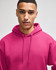 A man wearing a bright pink hoodie with a drawstring hood. The sweatshirt has a logo on it.