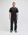 A black Champion adult short-sleeve t-shirt displayed on a model, paired with black pants. The shirt features a logo.