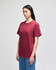 A maroon short-sleeve t-shirt on a model, featuring a logo on the sleeve.