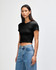 A fitted black women's crop t-shirt with short sleeves. The model is wearing it with high-waisted jeans.