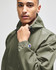 A man wearing a green Champion packable anorak jacket with a hood, featuring a logo on the sleeve.