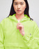 A packable anorak jacket in vibrant lime green, featuring a front pocket and adjustable hood, with branding.