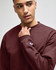 A maroon Champion Powerblend® adult full-zip hooded sweatshirt with a logo on the sleeve. The model is posing thoughtfully.