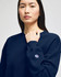 A navy blue women's crewneck sweatshirt with a logo on the sleeve, featuring a relaxed fit.