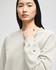 A grey Champion Powerblend® women's crewneck sweatshirt with a logo on the sleeve, worn by a model.