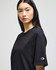 A black Champion Adult Heritage Jersey T-Shirt on a model, featuring a logo on the sleeve.