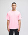 A pink Champion Adult Heritage Jersey T-Shirt displayed on a male model, featuring a logo on the sleeve.